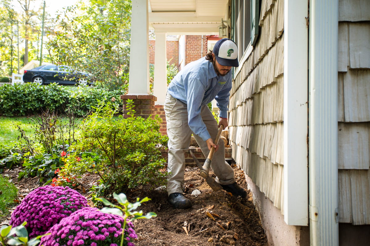 pest control technician digs trench to kill termites