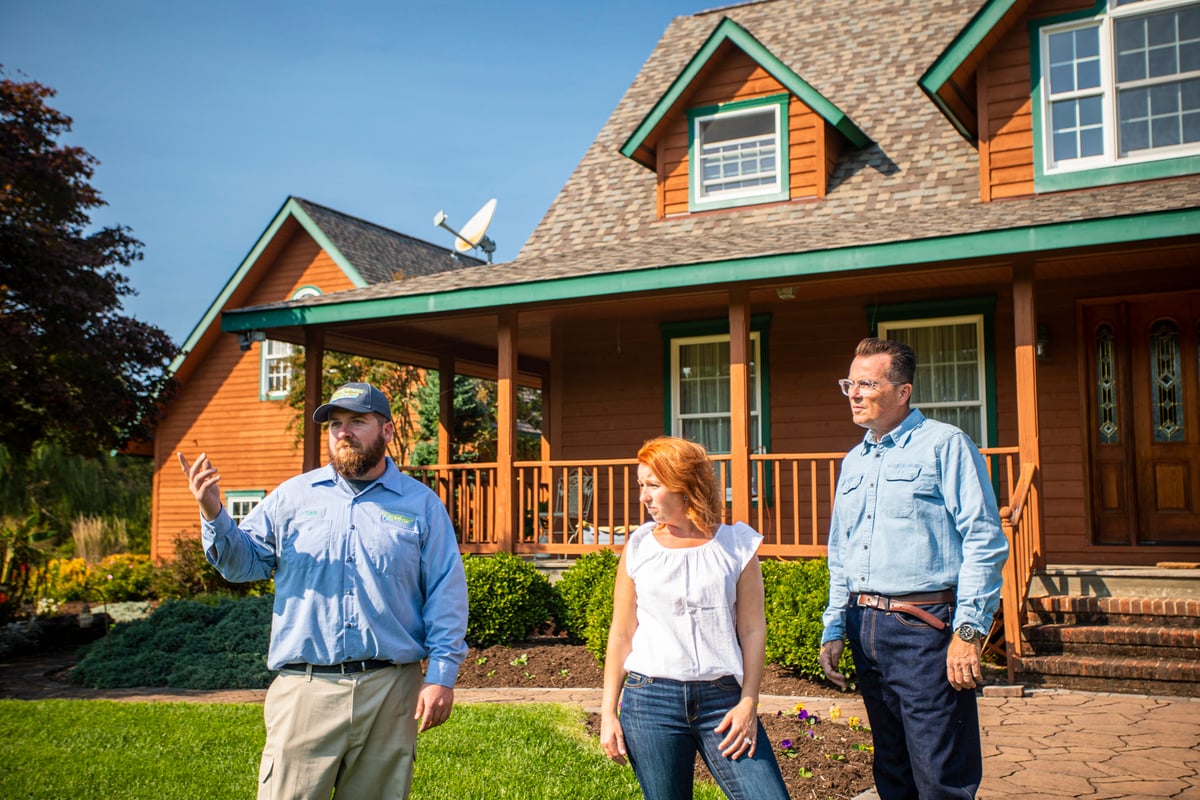 lawn care technician inspects lawn with customers