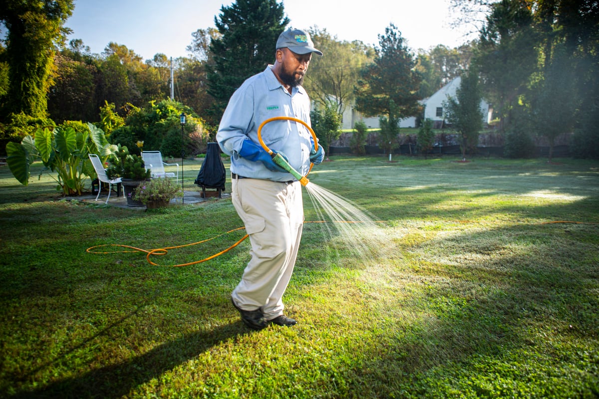 lawn care technician sprays for weeds