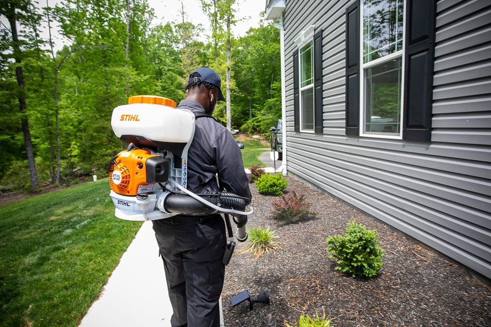 pest control technician sprays for mosquitoes