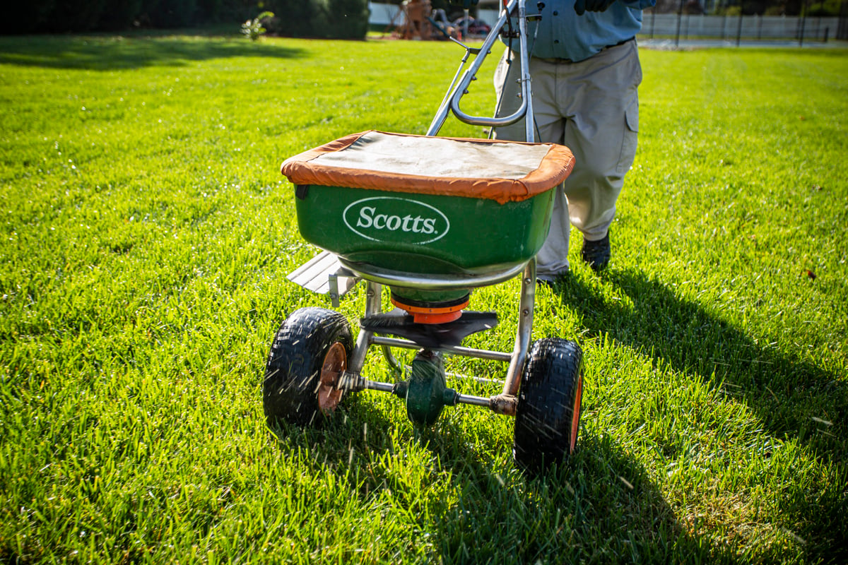 lawn care technician fertilizes lawn