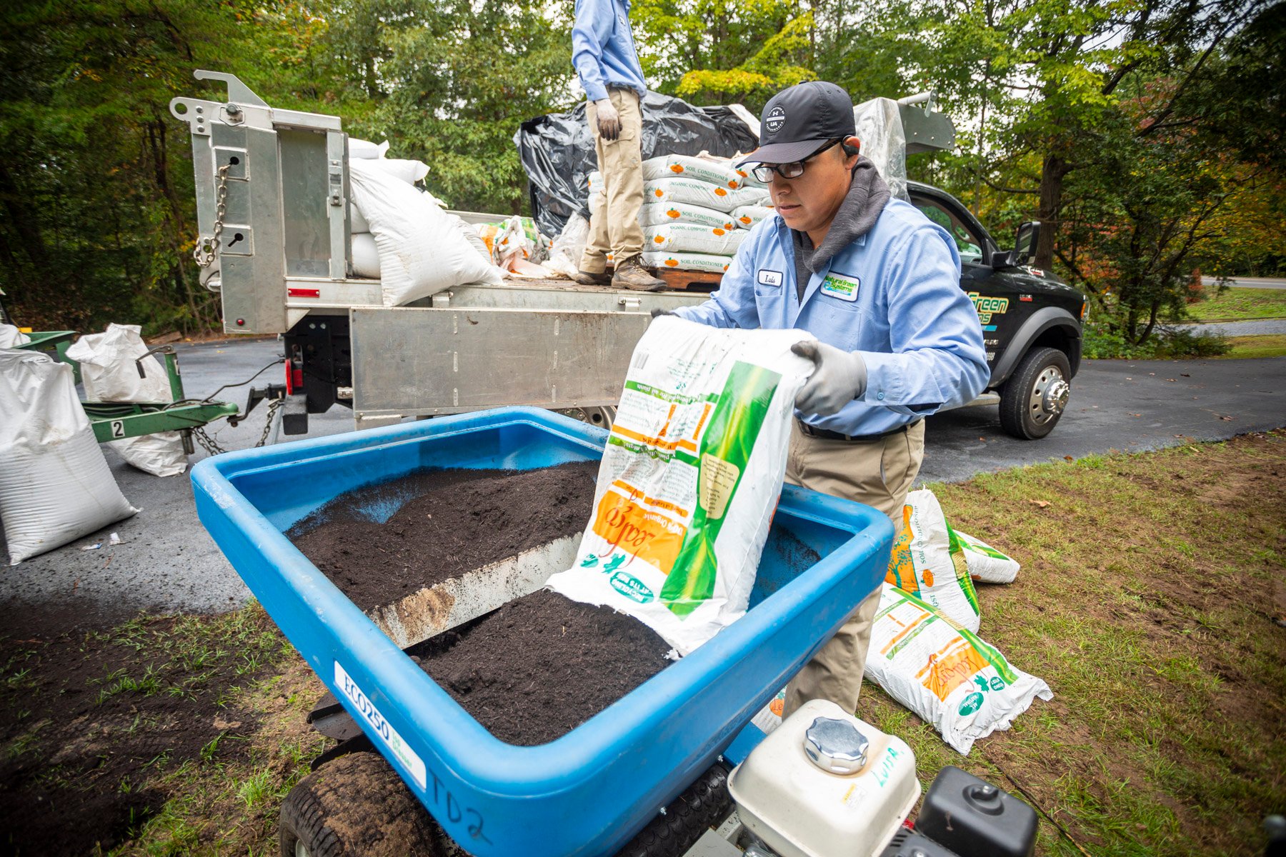 lawn care technician loads topdressing into spreader