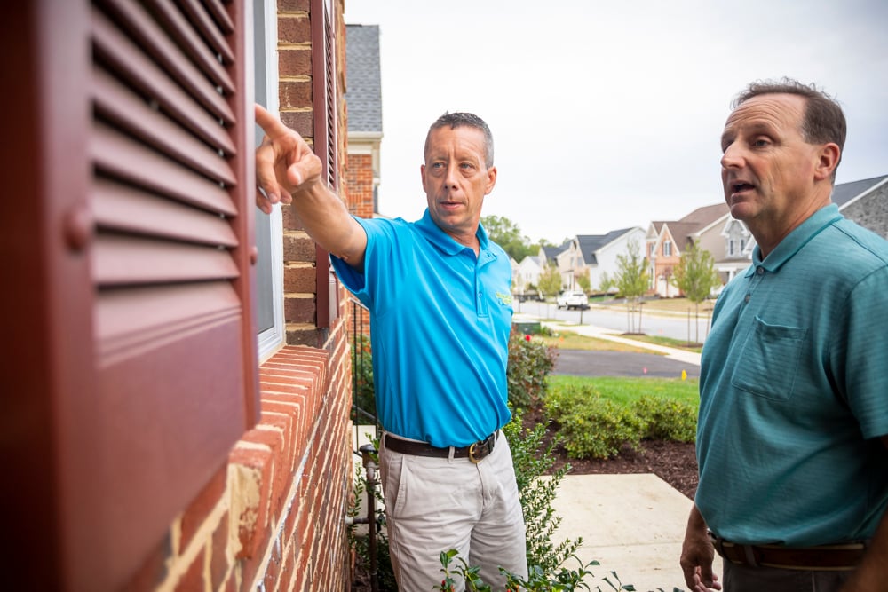 pest control technician shows client issue on window