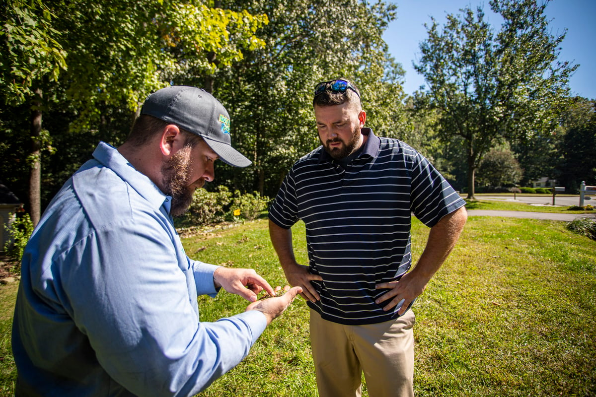 lawn care technician consults with customer