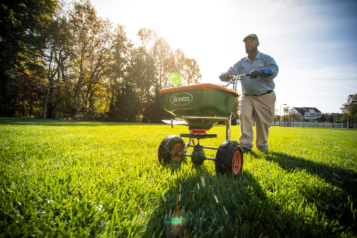 lawn care technician fertilizes lawn