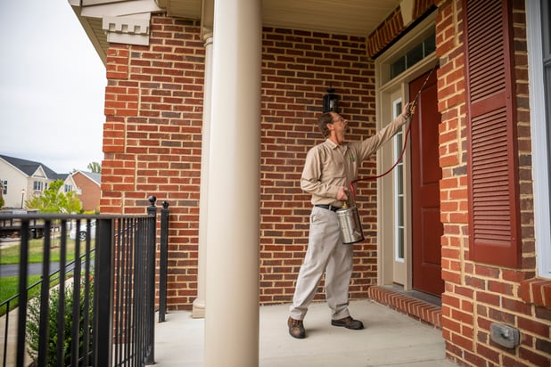 pest control technician spraying front door