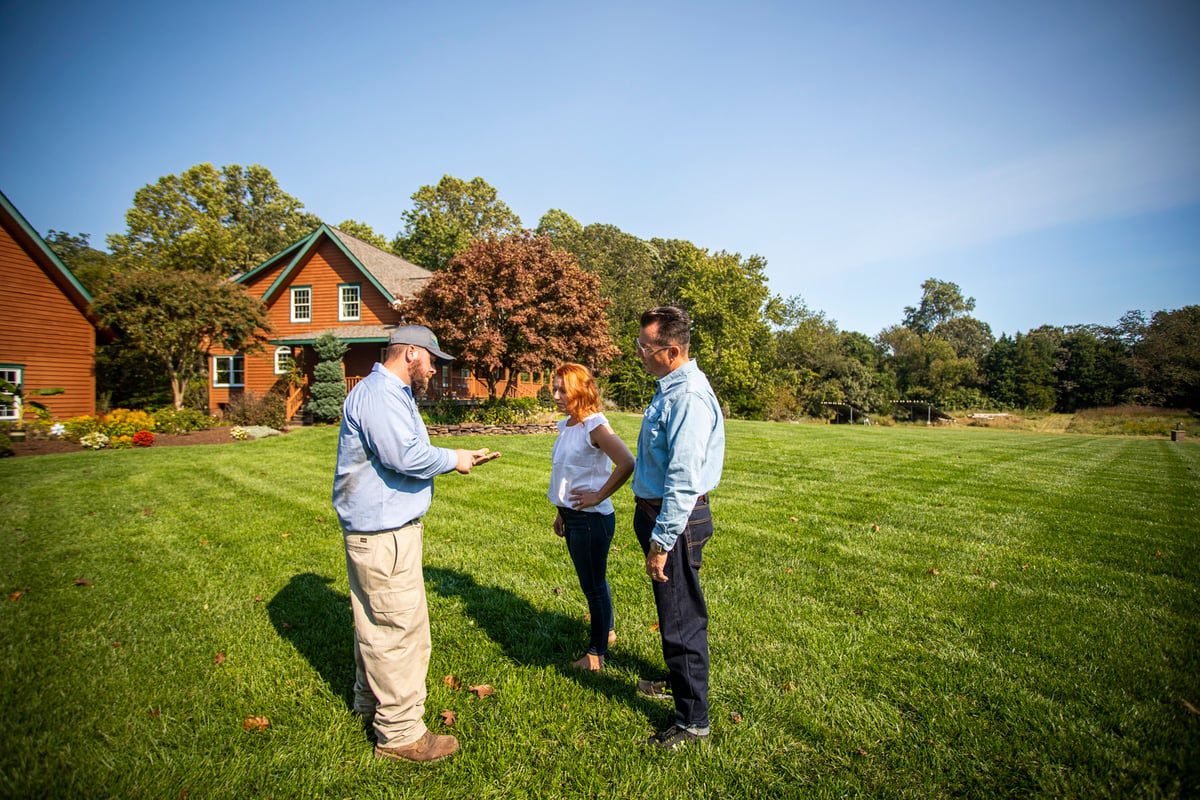 lawn care technician meets with customers on lawn