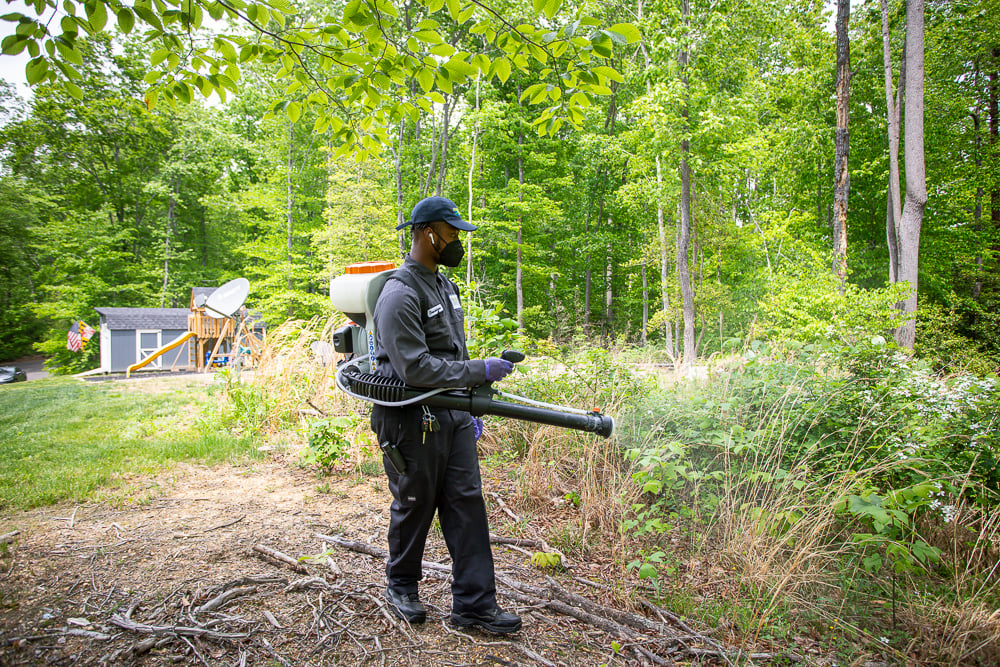 pest control technician sprays for mosquitoes