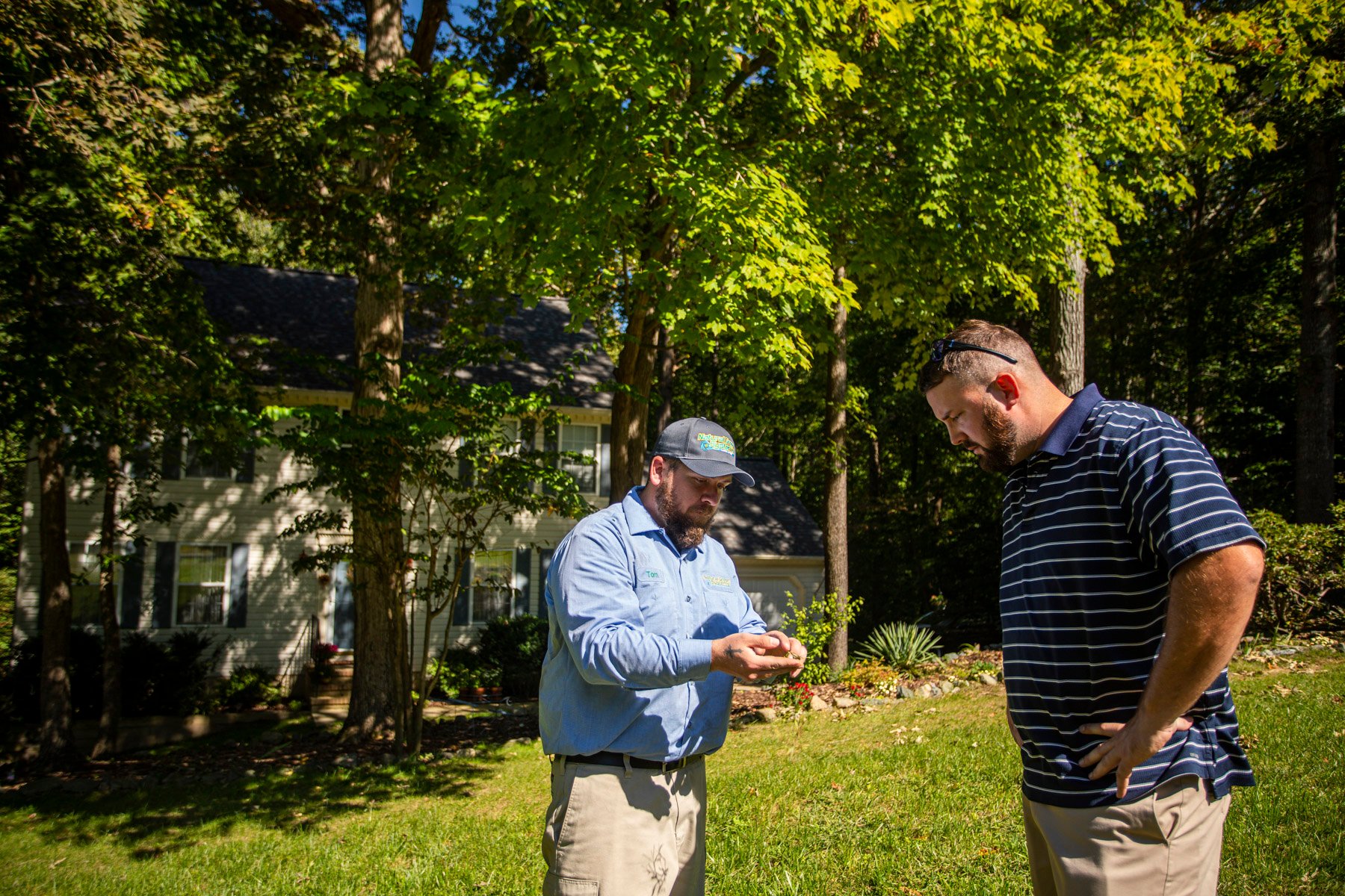 NaturalGreen lawn care technician inspecting lawn with customer