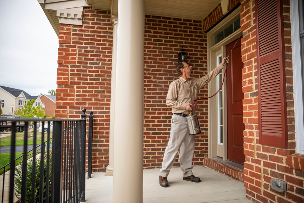 pest control applying spray to a home